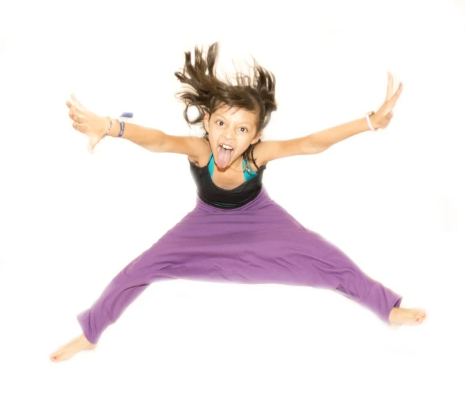 a young woman is jumping in the air with her arms spread out