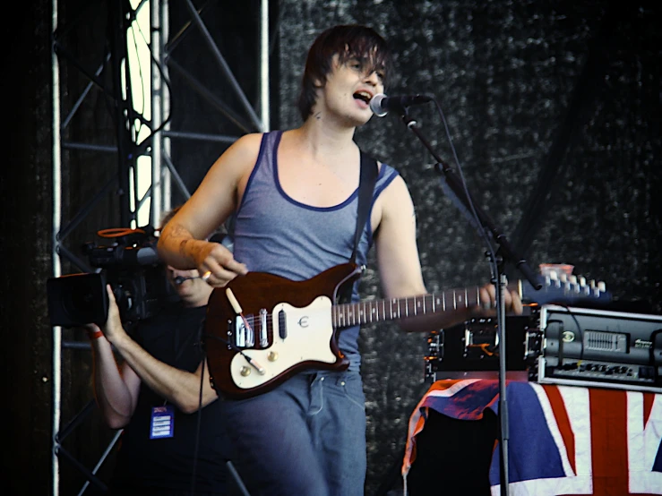 young male with short hair playing the guitar on stage