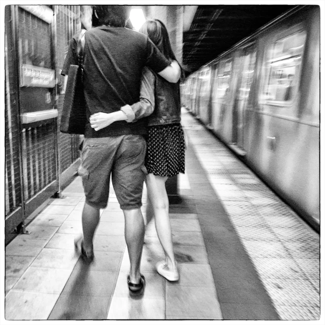 a couple walks down the platform with their back to each other