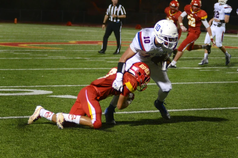 a football player falling while he is grabbing the ball