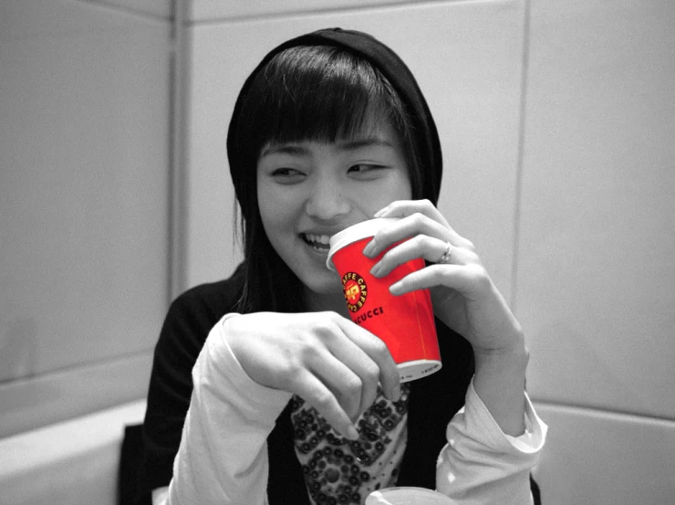 a young woman holding up a red cup in her hands