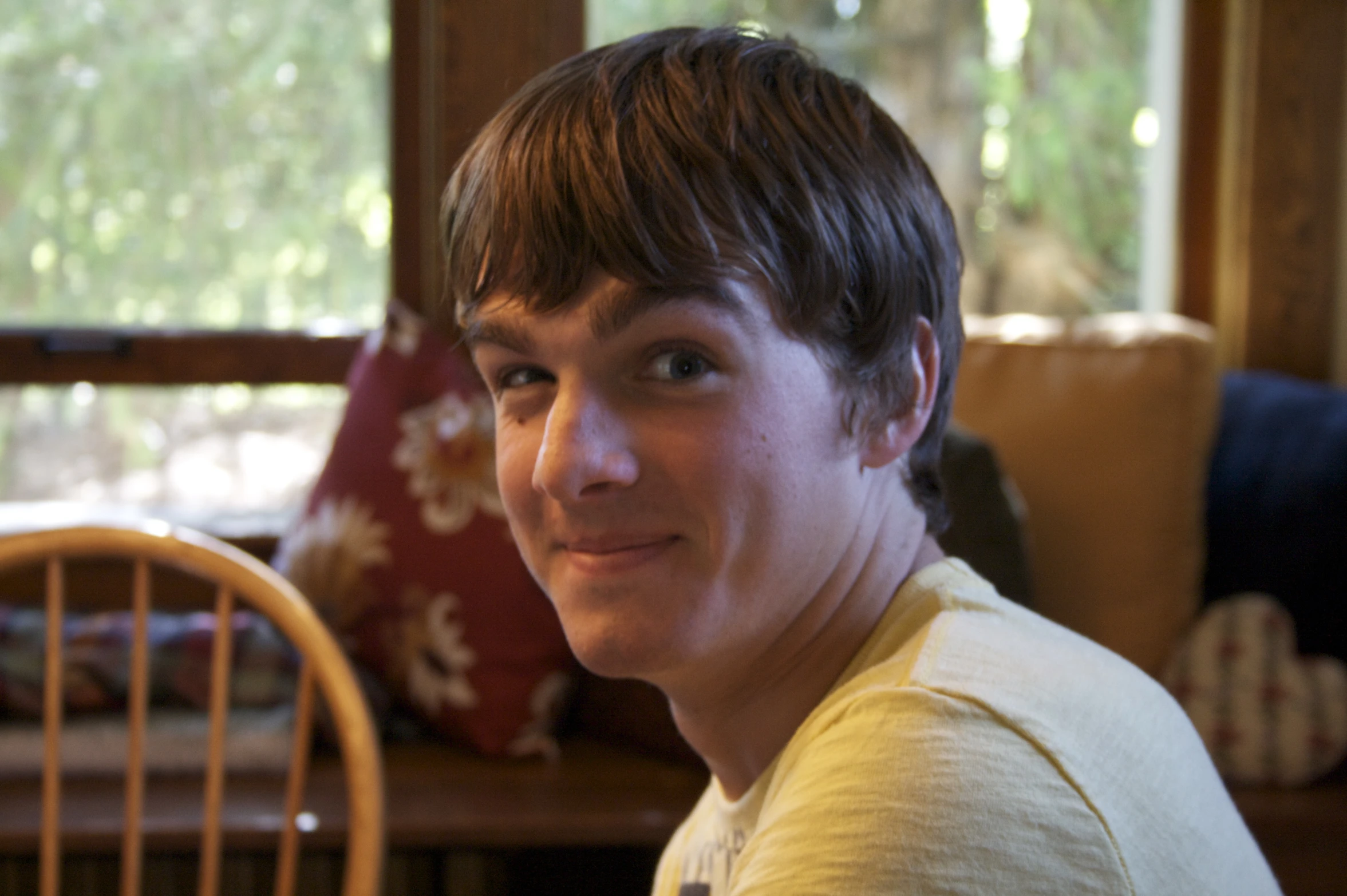 a man with brown hair sitting in front of a chair