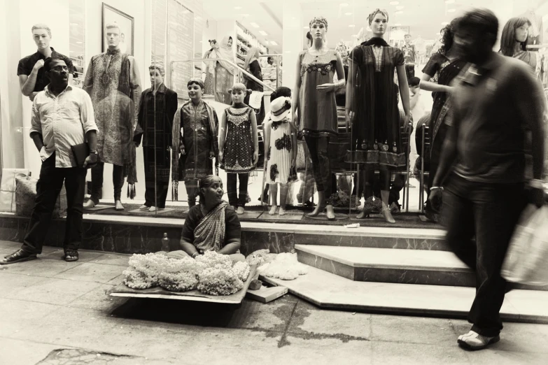 a black and white po of a man sitting in front of clothing store