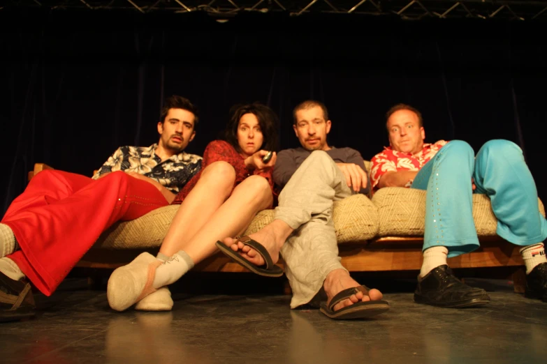 people sit together on a couch in front of a stage