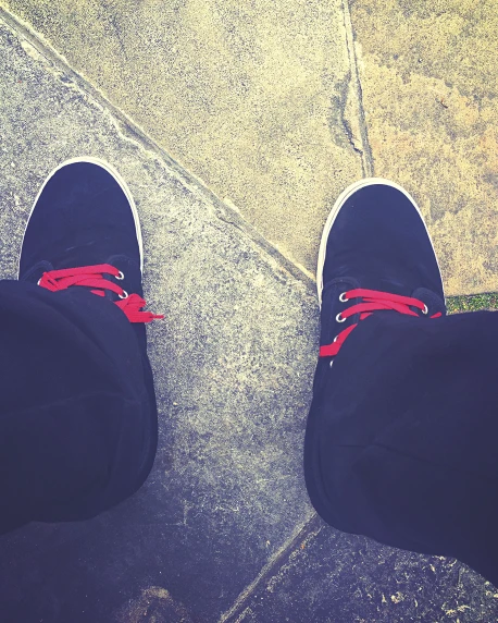 a pair of feet on pavement with red laces