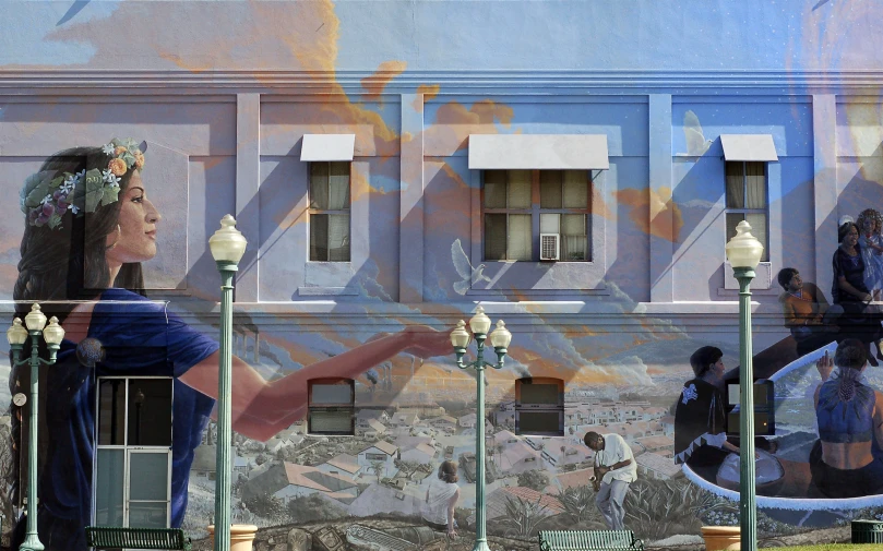 people stand on the side of an old building with a mural on it