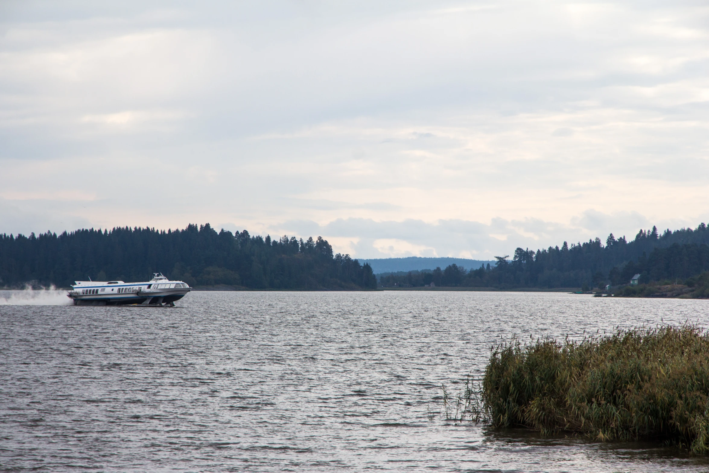 a boat travels across the water near grassy bank