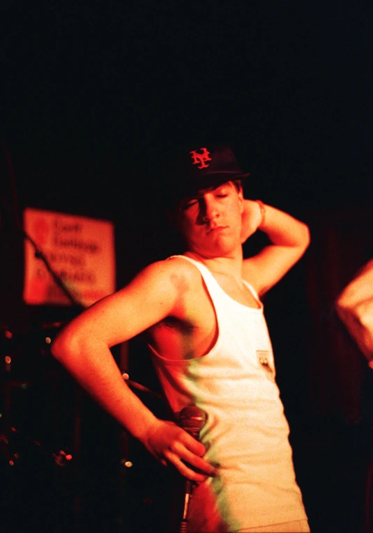 a young man in tank top with a microphone standing in front of him