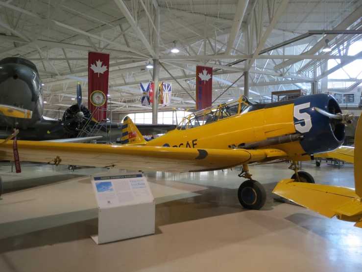 yellow fighter plane in large hanger with canadian flags