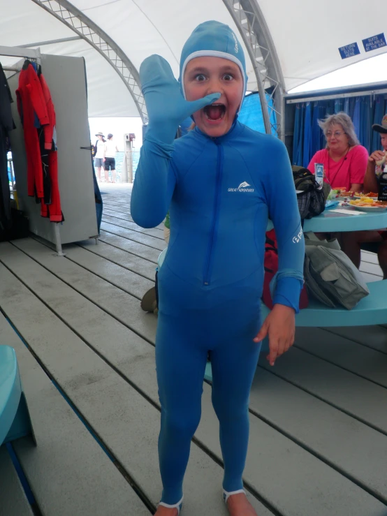 a boy wearing a blue swimming suit standing on a dock
