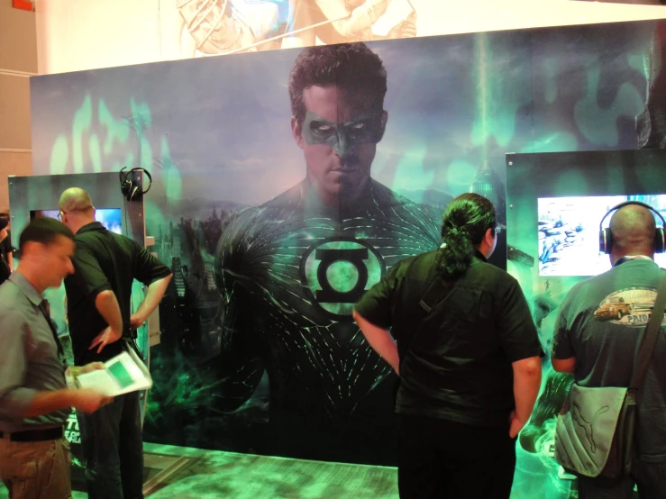 a man wearing green hair and a green mask stands near a wall with a movie poster