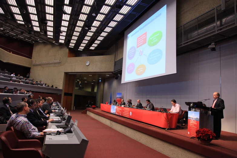 several people in a conference room listening to speakers