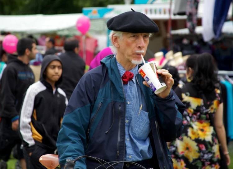 man standing in a crowd eating and drinking coffee