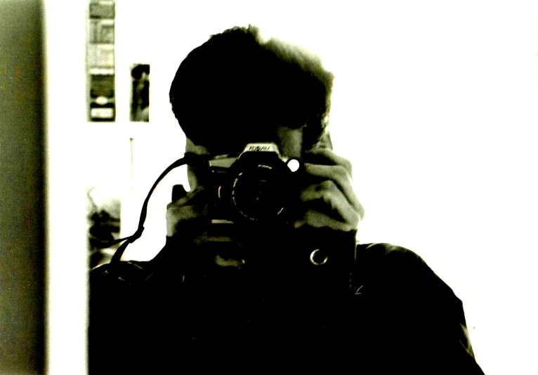 a person with a camera taking a picture in the mirror