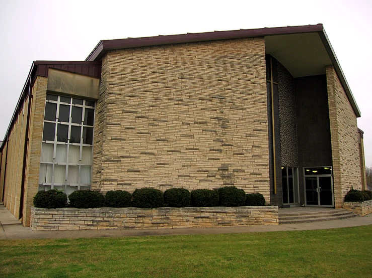 a clock outside of a building in front of green grass