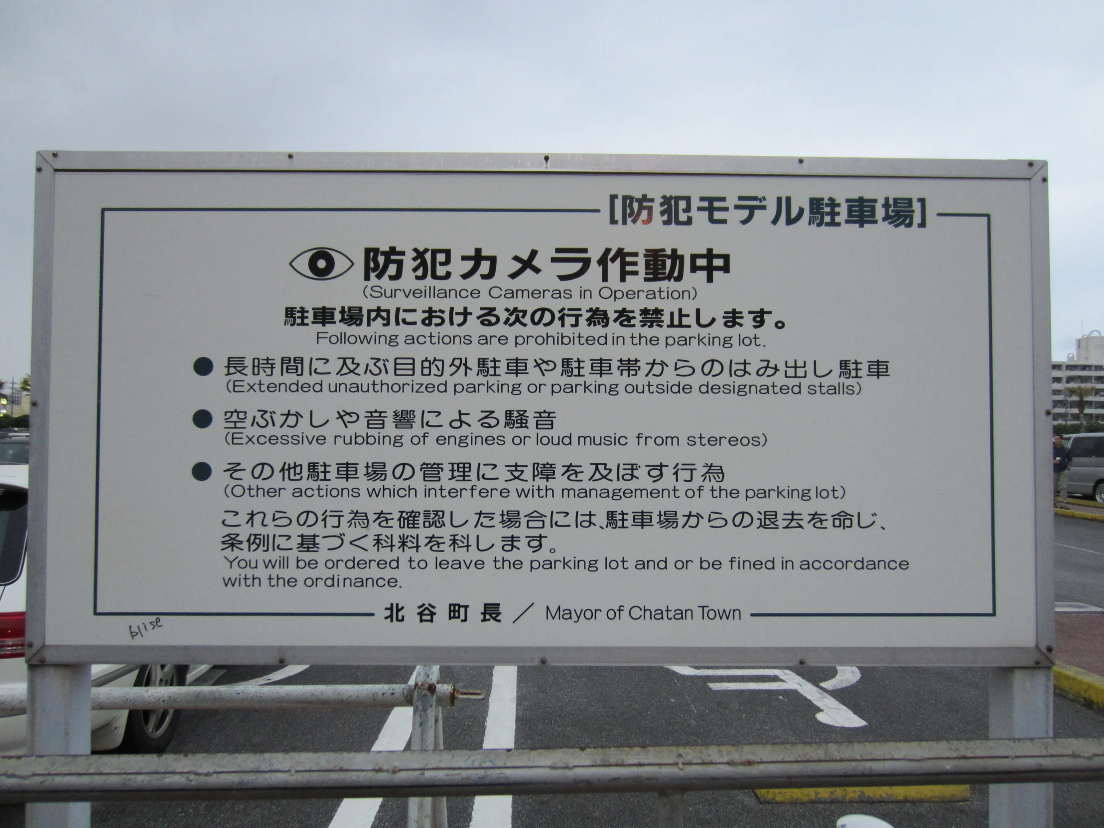 a sign in english and english sitting next to a metal fence