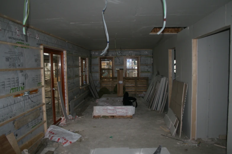 a room under construction with unfinished floors and a black cat laying on the floor