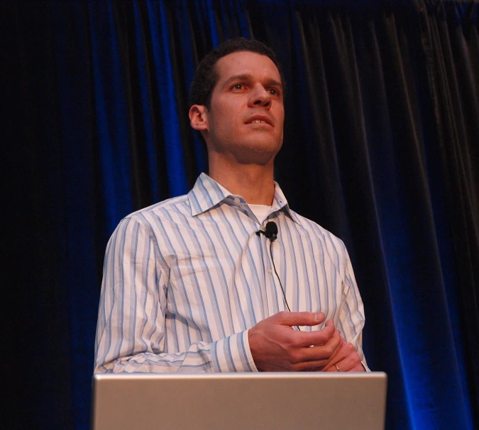 a man stands on a stage speaking to someone