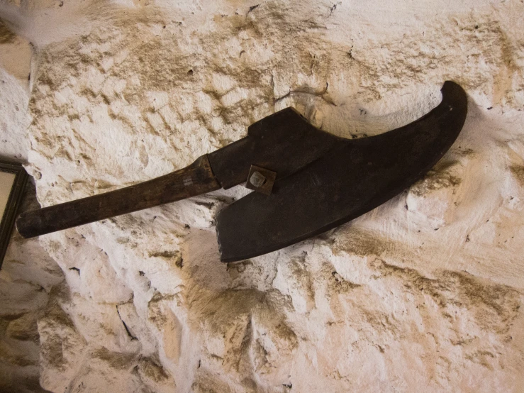 an ancient axe is displayed on a stone wall