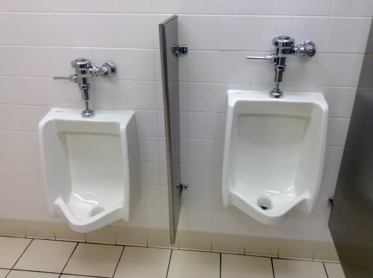 two urinals in a bathroom with tile walls