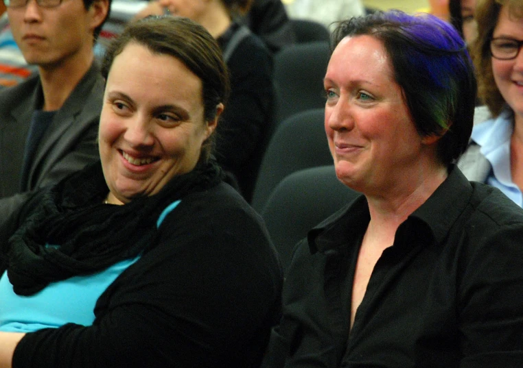 three women sitting in the front row, one smiling