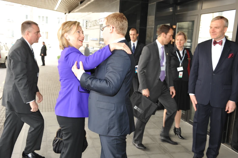 a woman is hugging a man in front of other people