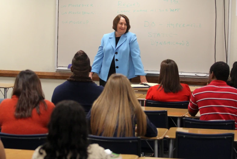 a woman is standing in front of a class while talking to students