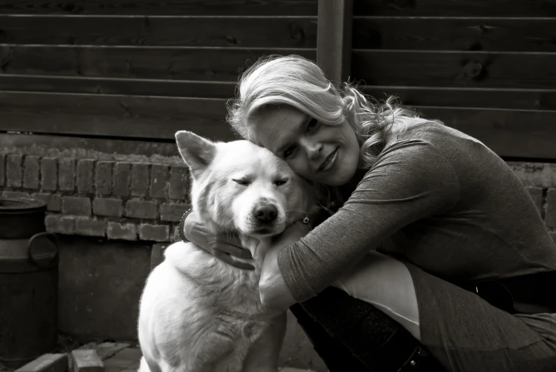 woman and white dog hugging each other in black and white