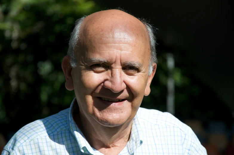 a man who is smiling with trees in the background