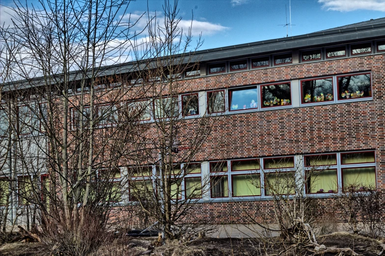 a brick building with trees and bushes growing in front of it