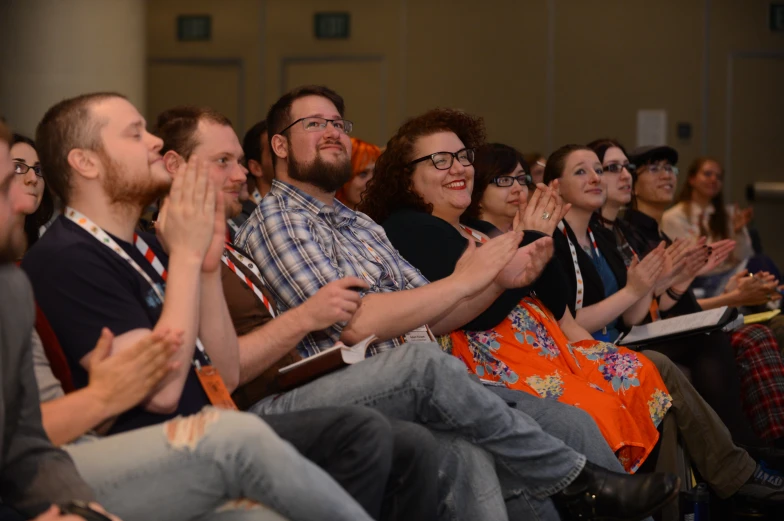 several people in an audience applauding at an event