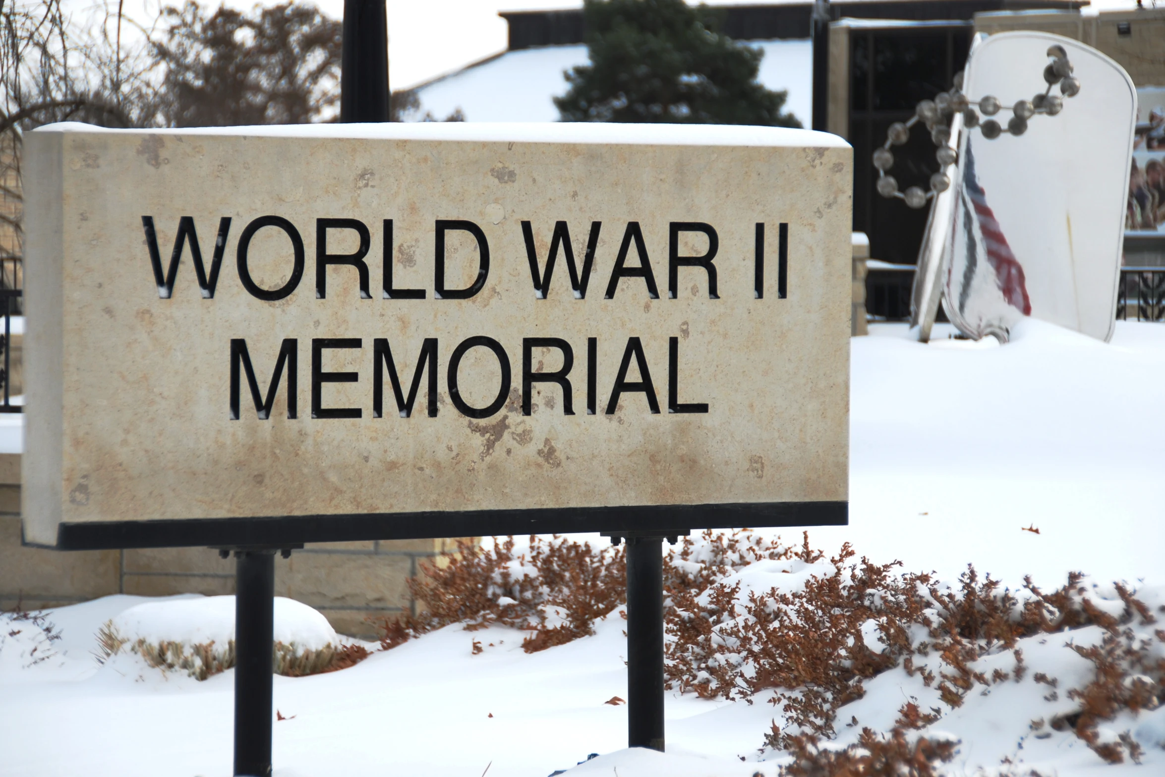 a war memorial sign in the snow by buildings