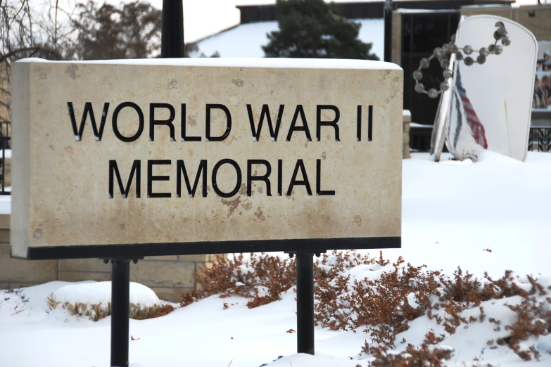 a war memorial sign in the snow by buildings