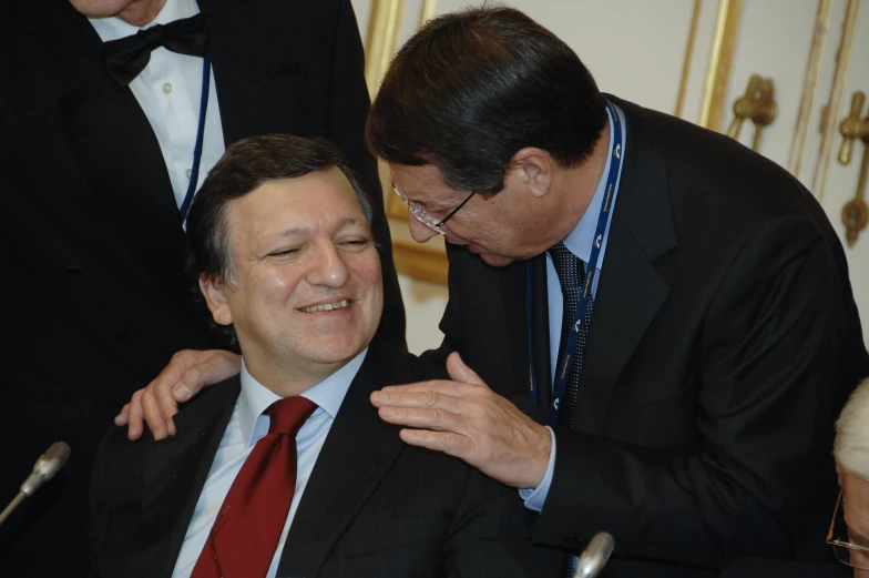 a man wearing a red tie is smiling while touching another mans chest