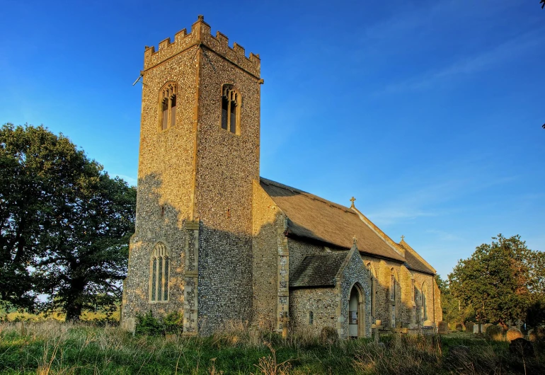 a church sits behind trees on the sunny day