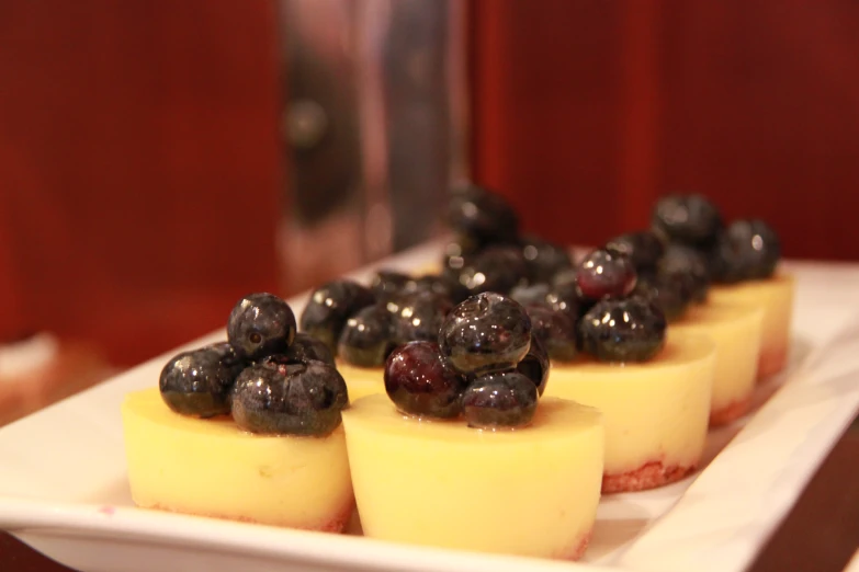 small cheesecakes with berries on them are on a white plate