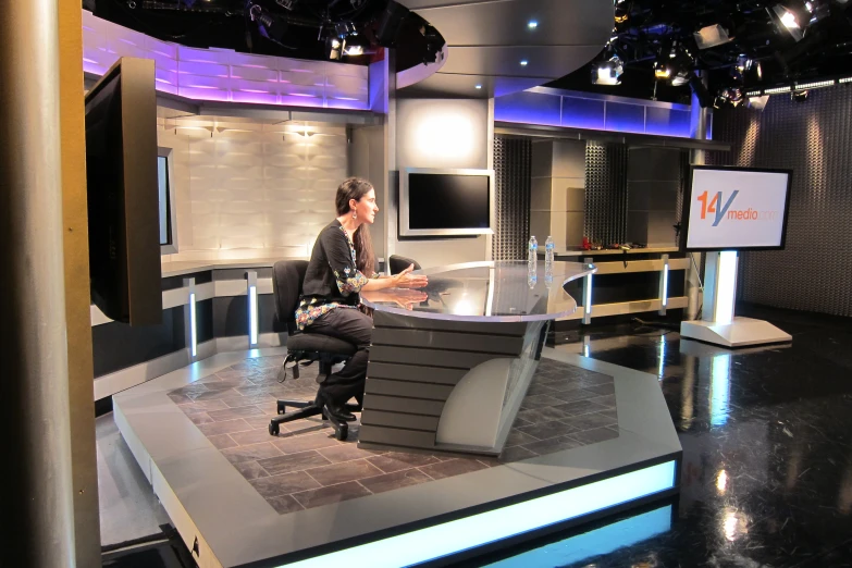 a man sitting on a desk in a tv set