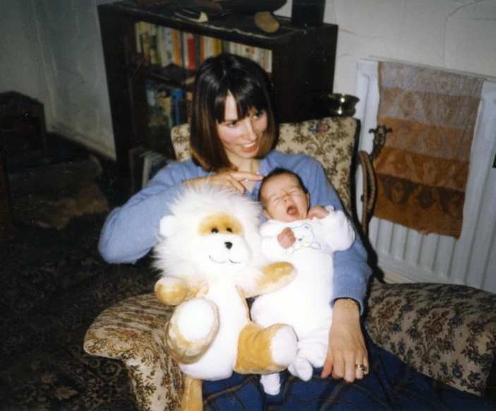 a woman holding a baby while holding a stuffed animal