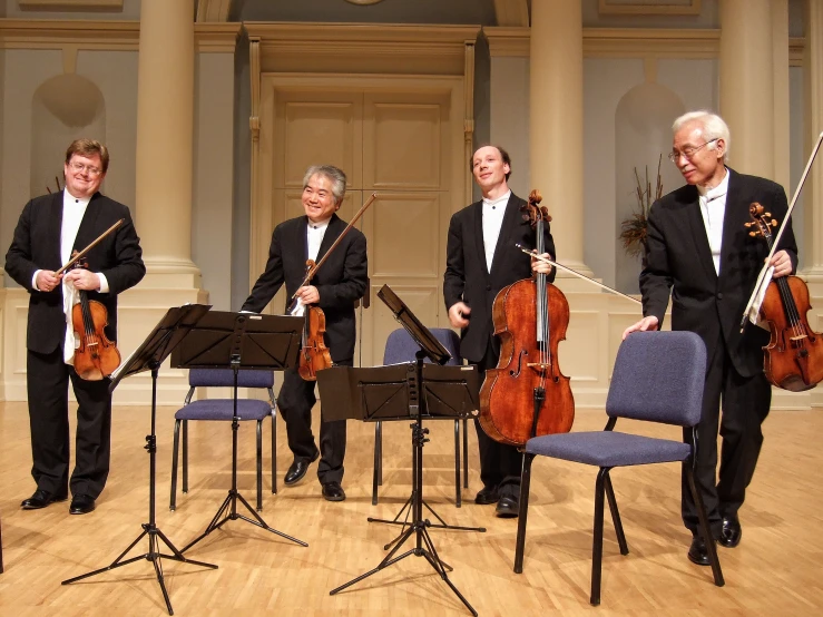 four musicians and one conductor are wearing black clothing