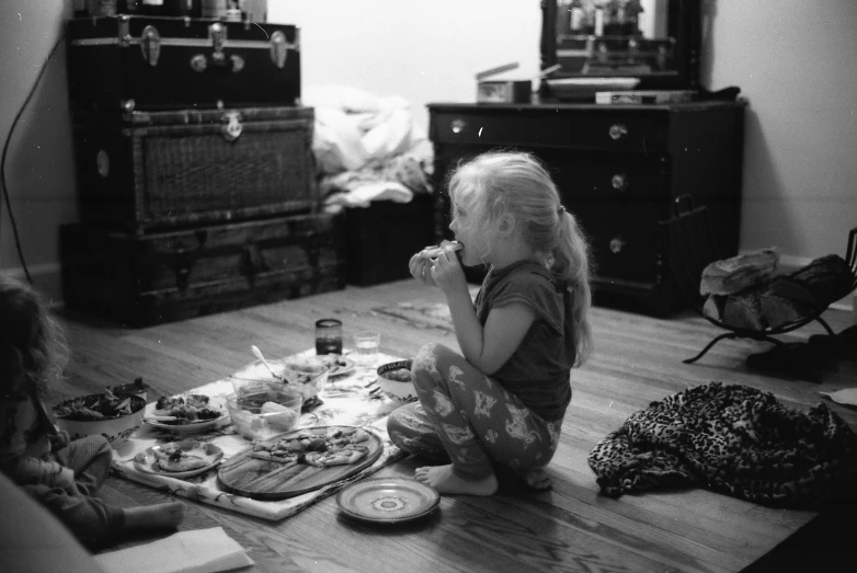 there is a girl sitting on the floor eating