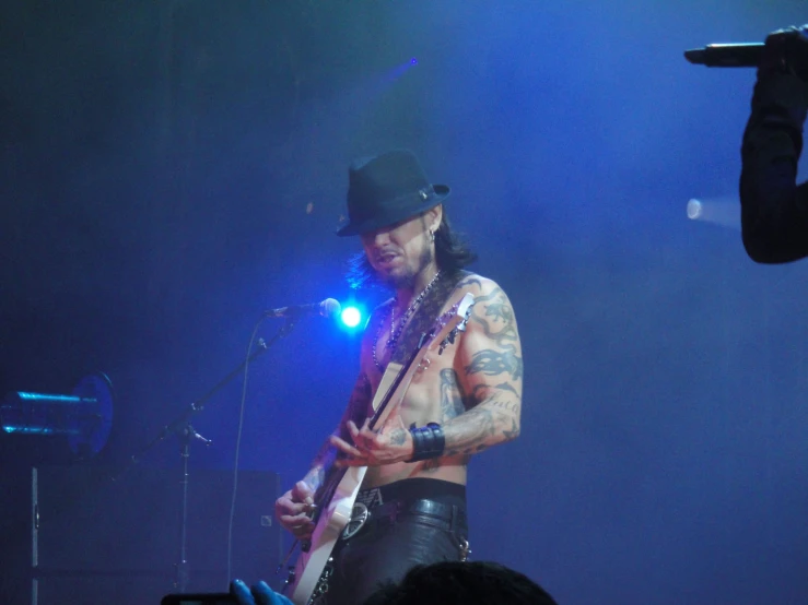 a shirtless guitarist is performing on stage