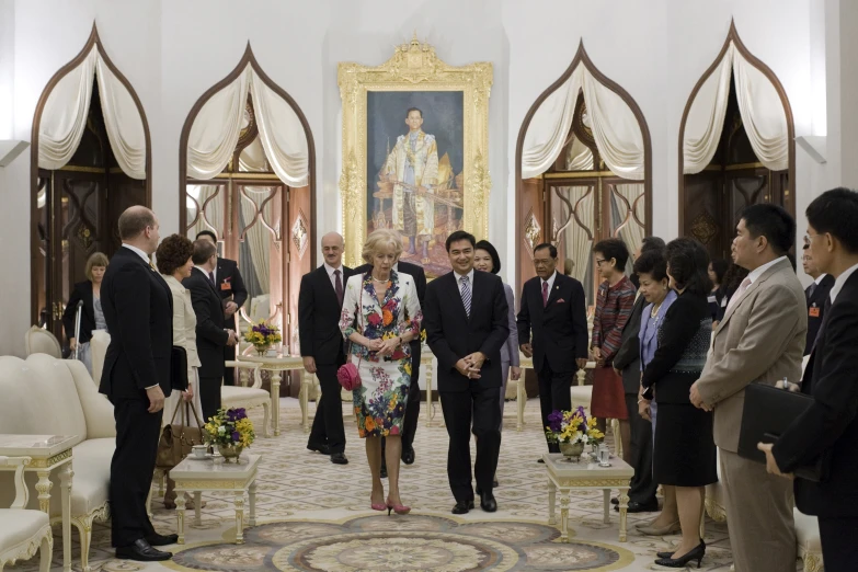 a man and woman are walking in a hall with an official portrait in the background