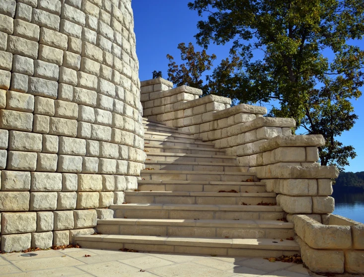 a stone staircase against a wall next to the water