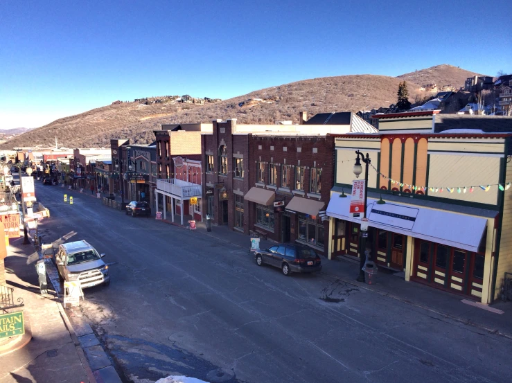 cars driving down an old - fashioned town street in the mountains