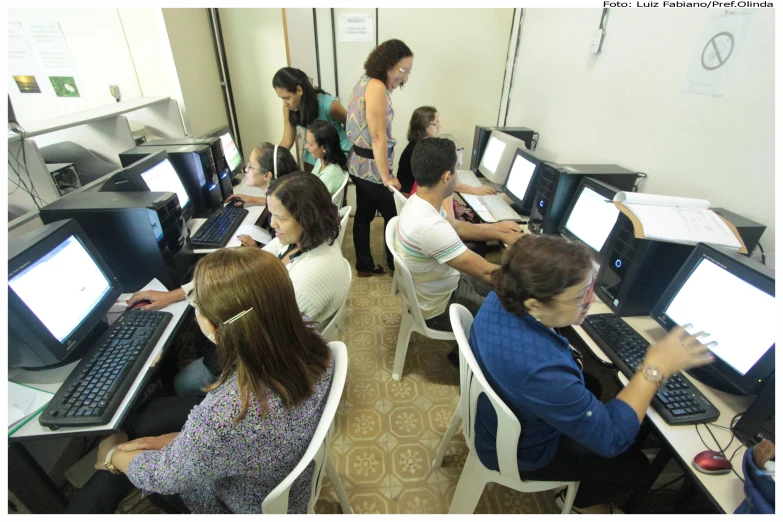 a classroom filled with computers and people standing