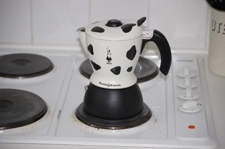 the coffee maker is on the stove with black spots