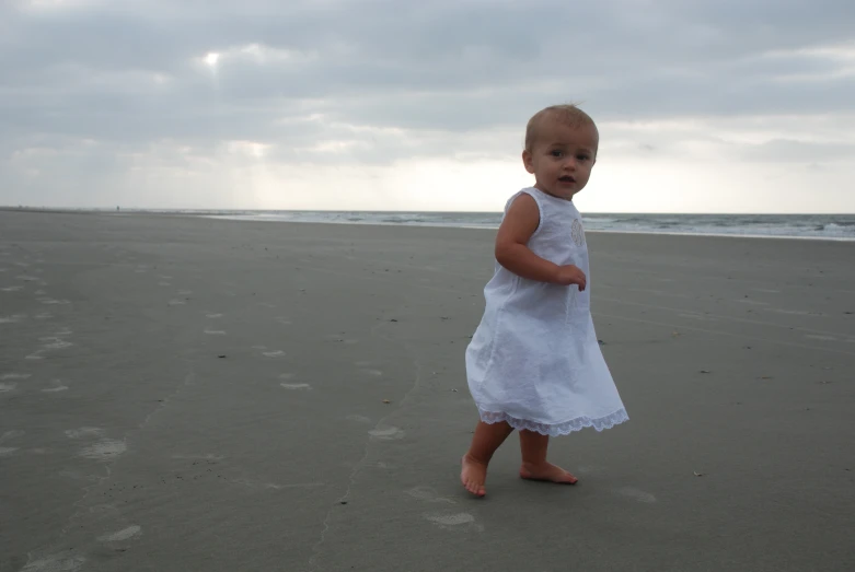 a baby is standing in the sand on a beach