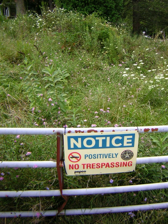 a sign hanging from a fence warning not to trespassing
