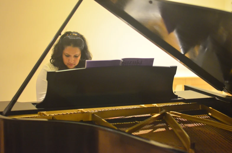 the young woman is playing a large piano