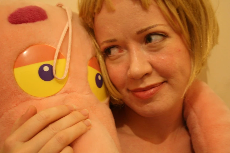 a woman is holding a stuffed animal with a red and yellow face